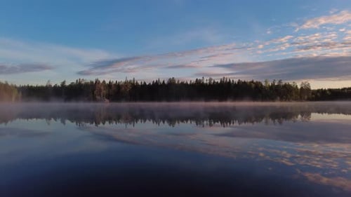 Summer sunrise by beautiful calm misty lake scenery in the wilderness. Beautiful reflection from the