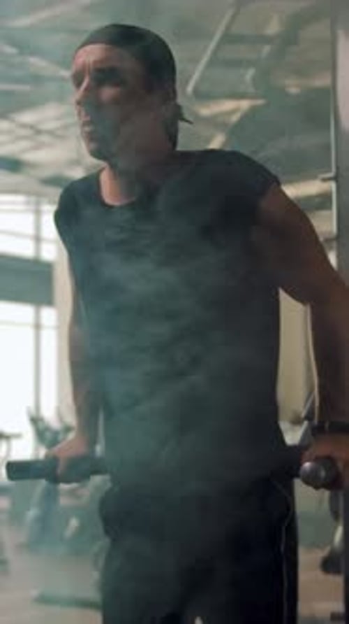 Vertical of A Mature Athlete in a Bandana is Doing Exercises on the Uneven Bars in a Gym