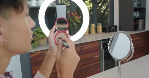 Young Adult Applying Makeup in Kitchen with Ring Light