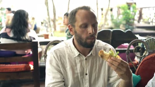 Young Man Eating Meal Sitting in Outdoor Cafe 30s