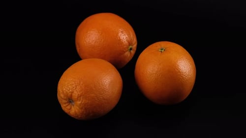 Frische Orangen in einem motorisierten Kamera-Slider auf schwarzem Hintergrund