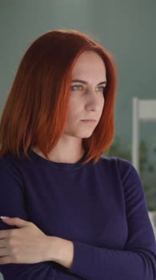 Une femme déprimée aux cheveux roux regarde par la fenêtre lumineuse