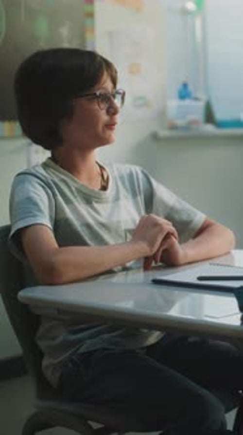 Primary School Children Sitting at the Desks Raising Hands to Give Correct Answer