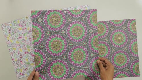 Tilting ornate piece of paper with shiny gold foil mandala ornaments.