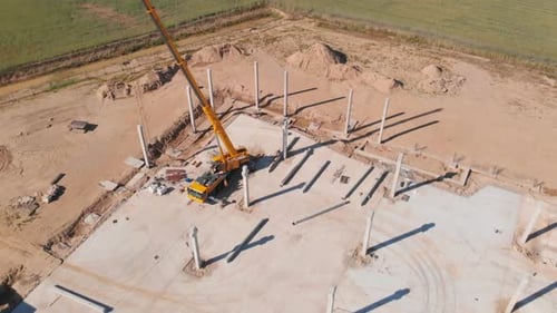 Construcción de una sala, piso de concreto, columnas y una grúa vertical