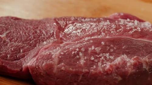 Man Chef Sault Pickle Rindersteakfleisch auf einem Schreibtisch aus Holz, Nahaufnahme, Makro, professionelle Zubereitung durch Chefkoch