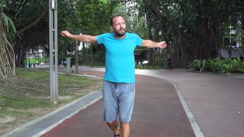 Young man warming up for jog in city park super slow motion at daytime