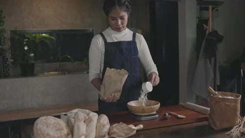 Woman scoops flour into bowl for baking bread