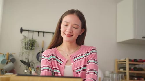 Young Adult Designs on Tablet in Kitchen