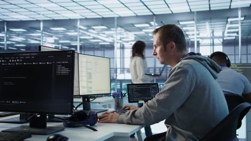IT Programmer Arriving at Work in Data Center Sitting at PC Desk