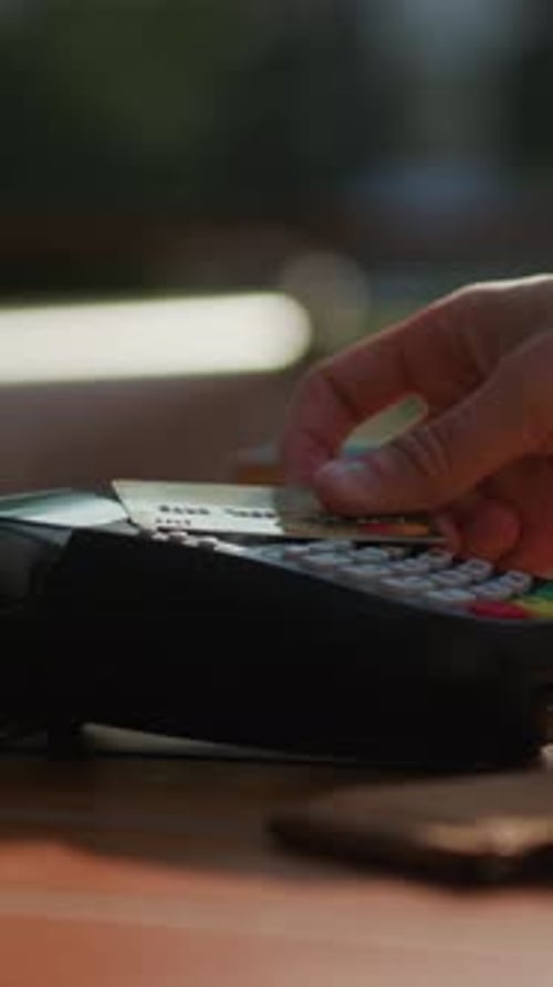 A Payment Terminal is Placed on a Wooden Table in a Bustling Restaurant Setting