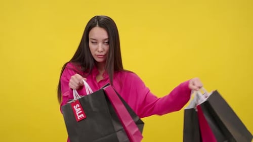 Young Woman Smiles with Shopping Bags on Yellow