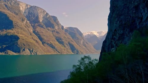 Sunlight shining on the high mountains at the Aurlandsfjord in Norway. Backwards drone dolley shot