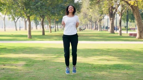 Energetic Woman Doing Jumping Jacks in the Park