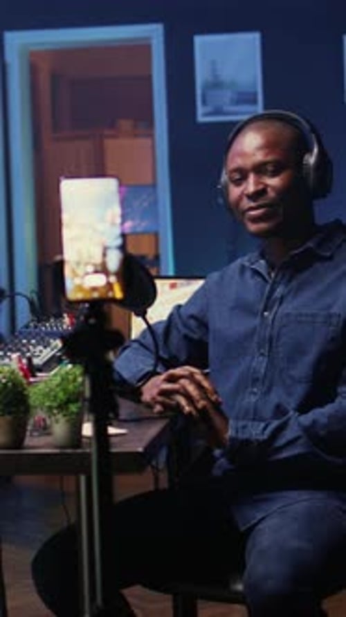Man Sits at Desk Broadcasting on Phone