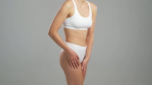 Young Fit and Beautiful Blond Woman in White Swimsuit Posing Over Grey Background Healthcare Diet