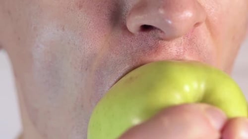 Man is eating green apple