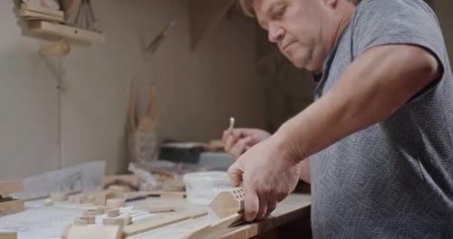 Woodworker Applying Glue on Wooden Detail in Workshop Tilt Up Side View of Concentrated Mature