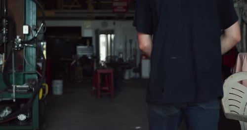 Professional Male Blacksmith Walking Into Workshop and Looking for a Piece Of