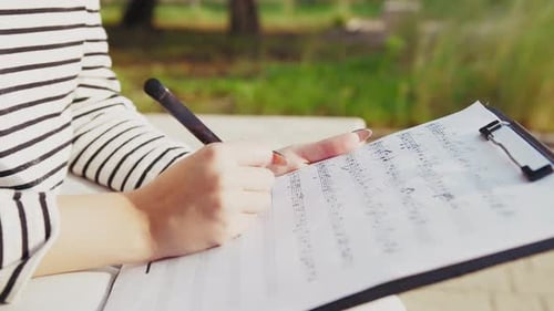 Girl Writes Notes On A Sheet Music To Play Them With The Ukulele