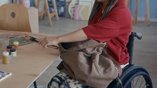 Female Artist with Disability Taking Out Brushes Preparing to Paint in Studio