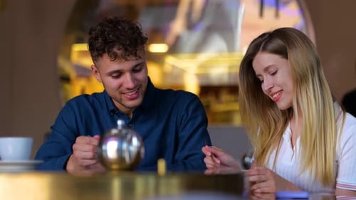 Happy Beautiful Couple in Love Sitting in Cafe While Woman Feeding Man