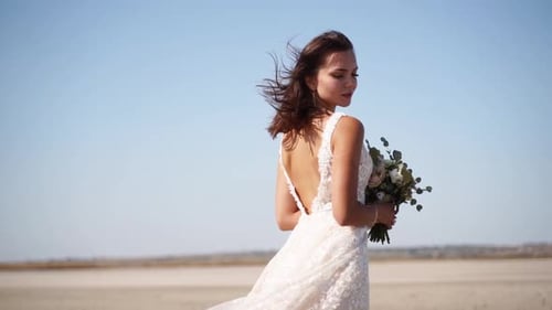 Happy Young Bride with Bouquet of Fresh Flowers Going at Desert Landscape Elegance Lady in Gorgeous