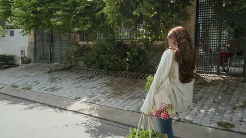 Mujer que lleva bolsas ecológicas con alimentos frescos cuando va a casa