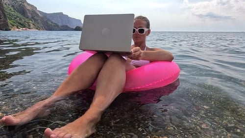 Woman Freelancer Works on Laptop Swimming in Sea on Pink Inflatable Ring Happy Tourist in Sunglasses