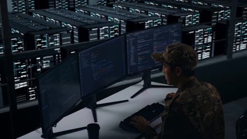 Side View Of Asian Military Using Computer To Write Code In Data Center