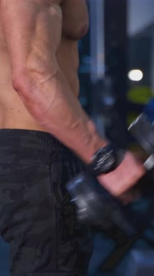 Man Working Out Biceps with Dumbbell at the Gym
