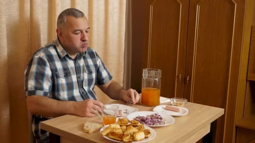 Adult Man Eating Sausage and Pastries Indoors