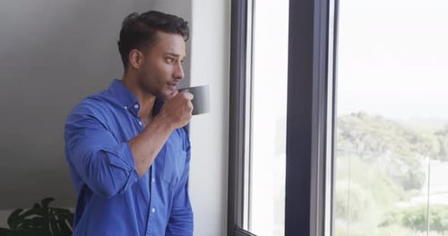 Man Drinking Coffee by Bright Window