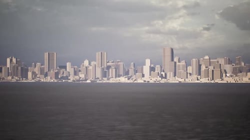 City Skyline Under Cloudy Skies Viewed From a Distance During Early Evening