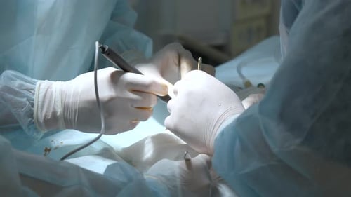 Skilled surgeons in white gloves performing manipulations with patient body at bright light