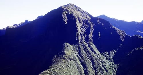 Majestic Mountain Peak Rises Above Rugged Terrain in Bright Daylight