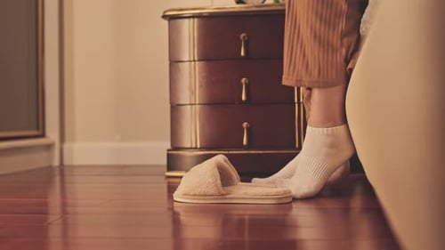 Femme méconnaissable portant des pantoufles se levant du lit