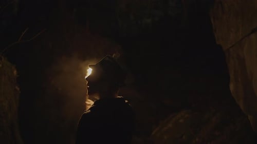 Man Exploring Dark Cave with Flaming Torch at Night