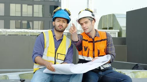 Zwei Ingenieure sitzen zusammen und überprüfen die Informationen aus dem Entwurf in Teamarbeit, Projektleiterplan