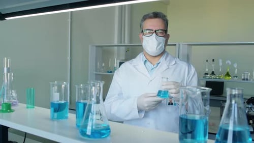 Scientist Holding Beaker with Blue Liquid in Laboratory