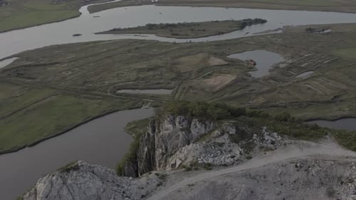 Parallax aerial shot of the riverbed down below an abandoned quarry on top of the mountain summit in