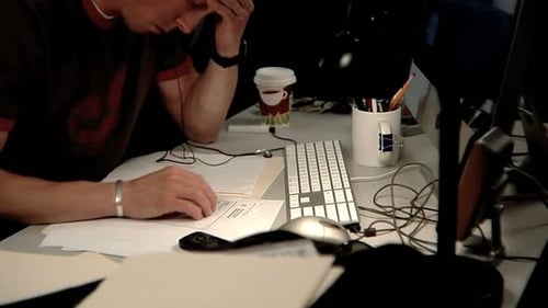 Homem trabalhando tarde da noite no escuro escritório digitando no laptop, examinando arquivos