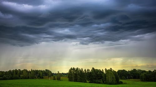 It is captivating to observe rain clouds gracefully gliding over a valley of lush green fields from