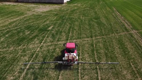 Aerial view of farming tractor spraying on field with sprayer, herbicides and pesticides insecticide