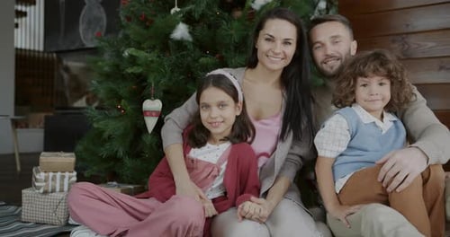 Happy Family Posing by Christmas Tree in Home