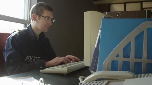 Police Officer Typing at Desk in Office