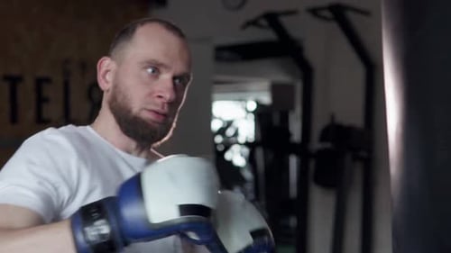 Male fighter in boxing gloves trains in the gym before a fight.