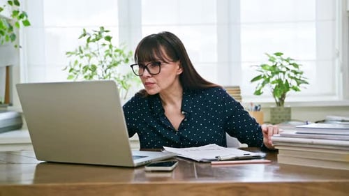 Middleaged Woman Working at Computer Laptop in Home Office