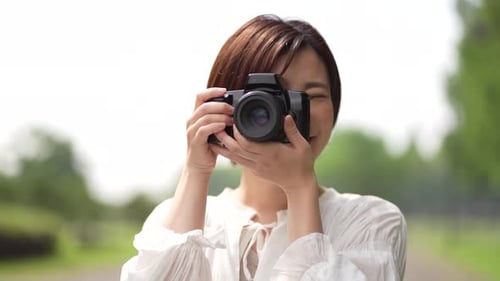 Smiling Woman Taking Pictures with Camera Outdoors