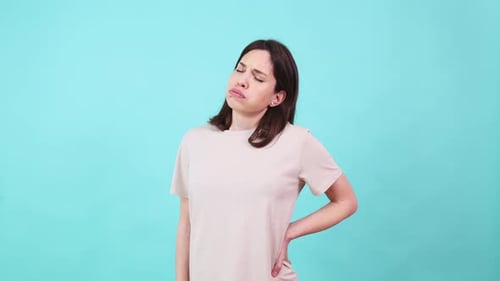 Woman Suffering From Back Pain on Turquoise Background